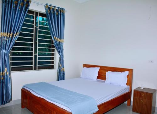 荣市Vinh Airport Hotel的一间卧室配有床和蓝色窗帘的窗户