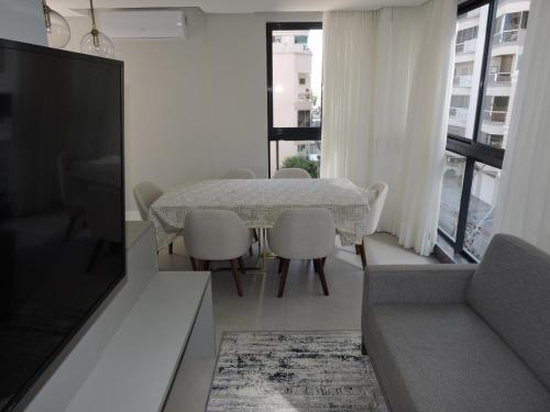 伊塔佩马Apart moderno 3 suites 2 vagas de garagem e quadra do mar的客厅配有桌椅和电视。