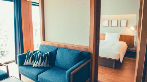 那霸Southwest Grand Hotel的客厅配有蓝色的沙发和床。