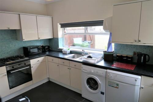 Thamesmead2 Bedroom cosy stay in Barking的厨房配有水槽和洗衣机