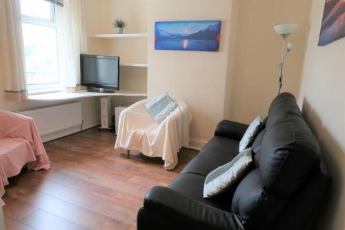 Thamesmead2 Bedroom cosy stay in Barking的客厅配有黑色沙发和电视