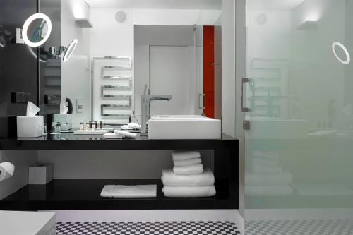华沙Renaissance Warsaw Airport Hotel的浴室配有盥洗盆、镜子和毛巾