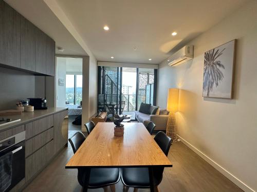 阿德莱德Luxury Top Level 1 Bedroom Apartment with Stunning View in Adelaide CBD - 1 minute walk to Rundle mall - Free Wifi & Netflix的厨房以及带木桌和椅子的客厅。