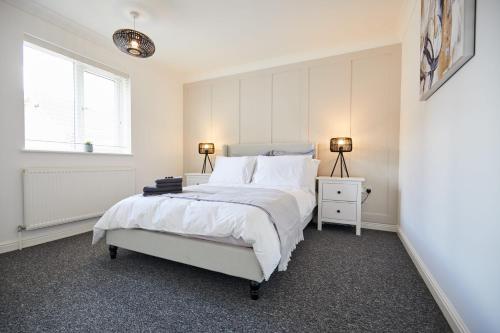 诺里奇Elegant Design 75" Smart Tv Long Stay Welcome的一间白色卧室,配有一张床和两盏灯