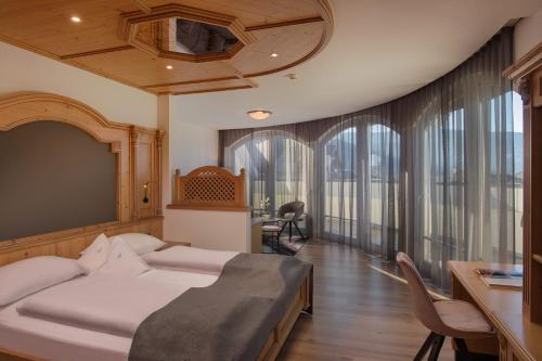 布鲁尼科Schönblick - Sport & Active Hotel的卧室配有一张床、一张书桌和窗户。
