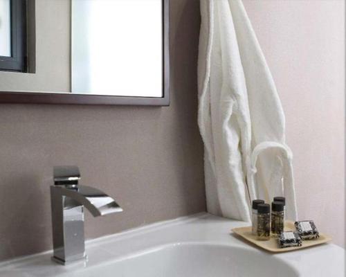 维蒂纳Natura Hotel Vytina的浴室水槽配有镜子和毛巾