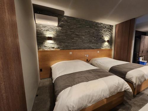轻井泽トライハク軽井沢 日向-ひなた-的一间卧室设有两张床和砖墙