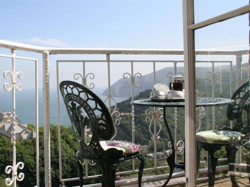 林顿Highcliffe House的阳台配有桌椅,享有风景。