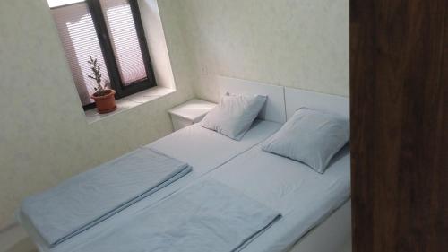 撒马尔罕Begzod's house的一张带两个枕头的白色床和窗户