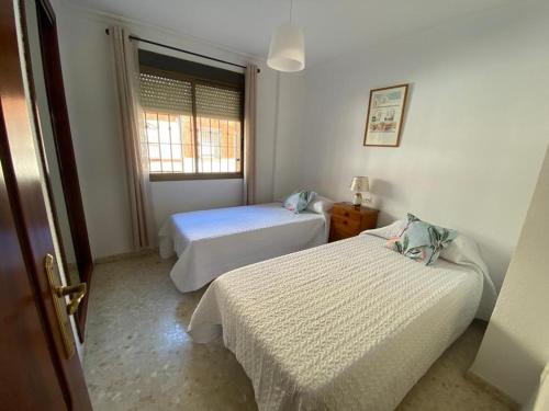 韦尔瓦Apartamento Familiar En Barrio Reina Victoria的一间卧室设有两张床和窗户。
