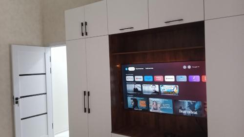 撒马尔罕Begzod's house的厨房配有白色橱柜和平面电视。