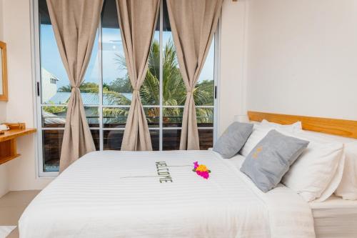 KendhooDhoani Maldives Guesthouse的卧室配有白色的床和窗户