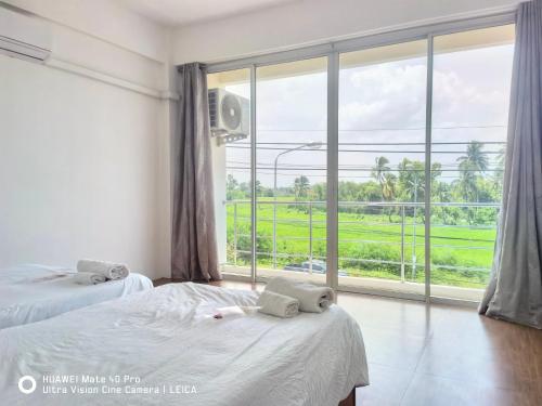 Ban Khlong KrangYYK Townhouse的一间卧室设有两张床和大窗户