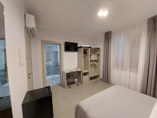 泰尔莫利Residenza Elba - Charme House的一间卧室配有一张床、一张书桌和一个窗户。
