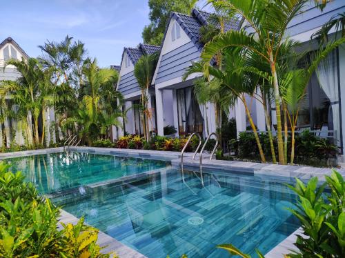 富国Ngoc Trai Xanh Bungalow的棕榈树屋前的游泳池