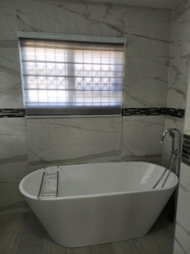哈博罗内Josmot Guest House的带窗户的浴室内的白色浴缸