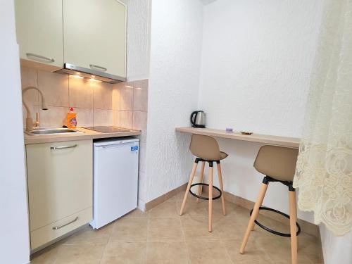 布德瓦MM Apartments的一个带柜台和两张凳子的小厨房