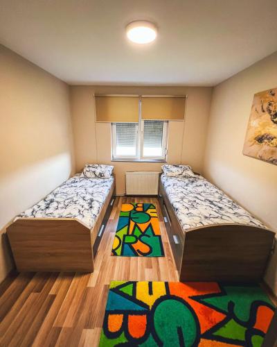 普里什蒂纳Don_house的小房间设有两张床,铺着地毯