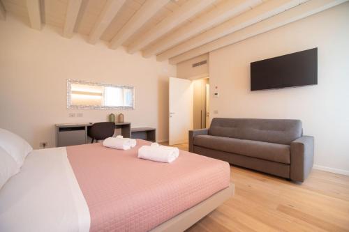 维罗纳Calcirelli Suites的一间卧室配有一张床、一张沙发和一台电视
