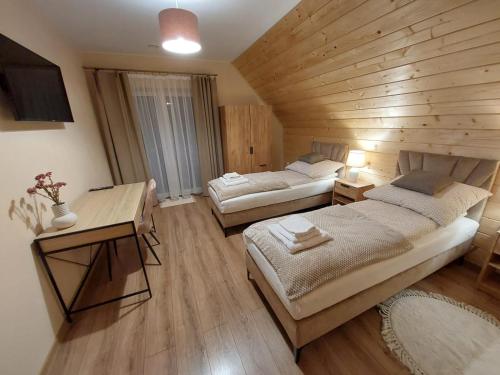 赖曼瑙-兹德鲁伊Agroturystyka Bliżej Natury的大房间设有两张床和木墙