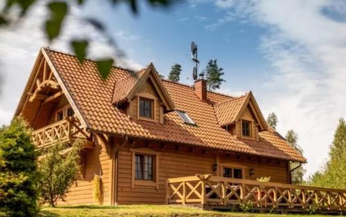 PodjazdyLeśny Dworek Podjazy的木房子,设有瓷砖屋顶