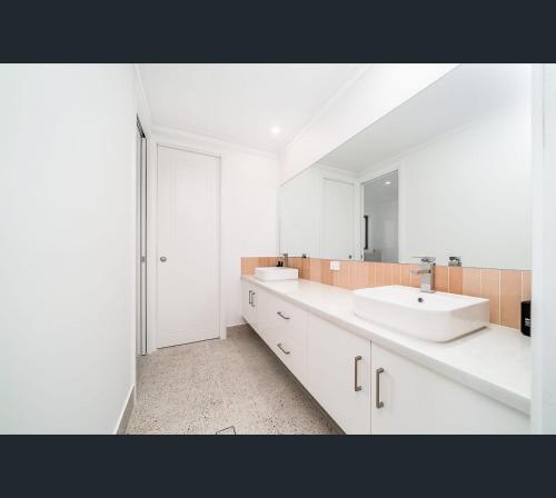 沃加沃加Brand New Luxury Abode on Shaw的白色的浴室设有两个盥洗盆和镜子