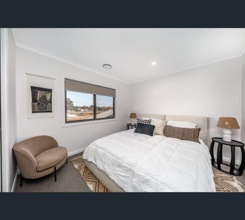 沃加沃加Brand New Luxury Abode on Shaw的白色卧室配有床和椅子