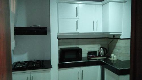 卡卢特勒GAYA HOMESTAY的厨房配有白色橱柜和微波炉