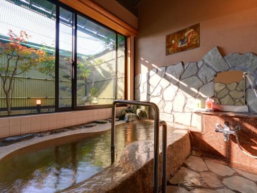 武雄市北方温泉四季の里　七彩の湯的带大窗户的客房内的热水浴池