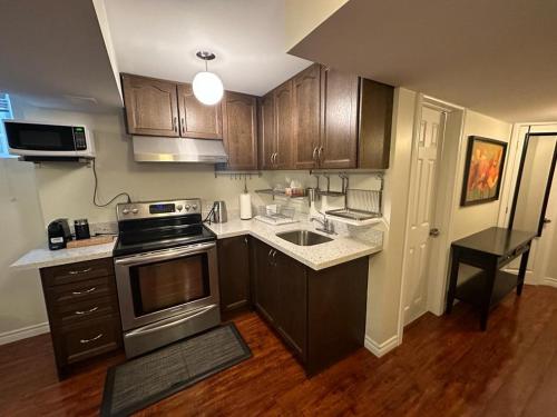 列治文山Basement apartment的厨房配有水槽和炉灶 顶部烤箱