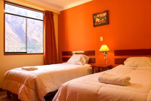 奥兰太坦波Inka's Haven Hotel的橙色墙壁和窗户的客房内的两张床