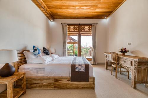 卡朗阿森Atta Villa的一间卧室配有一张床、一张书桌和一个窗户。