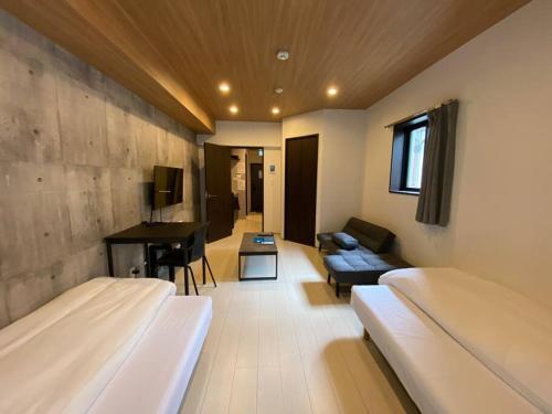 熊本リブレ in Kumamoto 302的客房设有两张床、一张沙发和一张书桌。