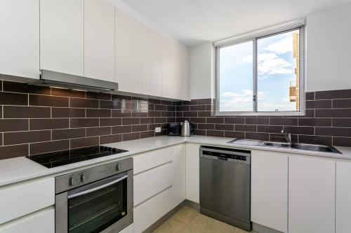 悉尼CRE31 - renovated 1 bedroom unit - Cremorne的厨房配有白色橱柜和窗户。