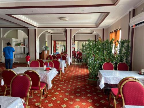 科洛尼亚CHINA STAR HOTEL的用餐室配有白色的桌子和红色的椅子