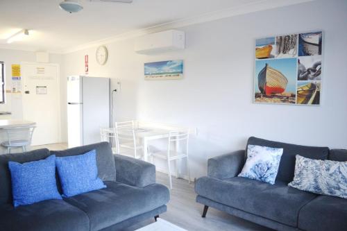 西南岩Village Centre 6的一间带2张蓝色沙发的客厅和一间厨房