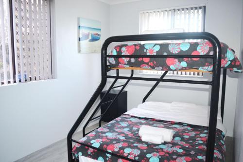 西南岩Village Centre 6的一间卧室配有一张双层床和花卉图案的毯子