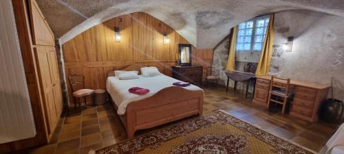 勒布伊Maison au Loup - Superbe ancien hotel particulier du XVIe siècle au cœur de la vieille ville du Puy的一间卧室配有一张床、一张书桌和一个窗户。