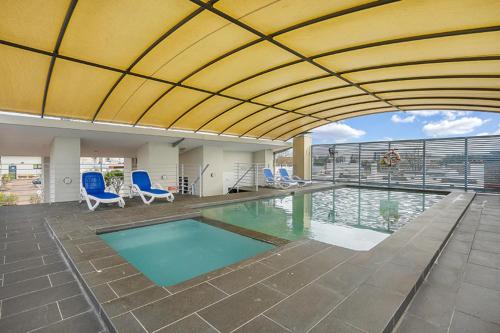 悉尼Contemporary Apartment的一座带蓝色椅子的游泳池和一座建筑