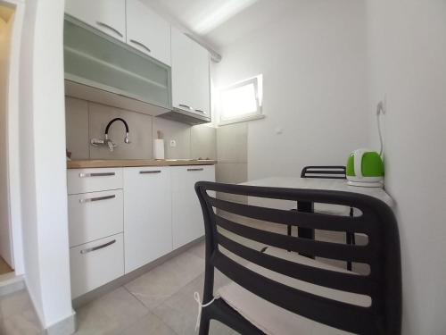 科尔丘拉Accommodation Drasko的厨房配有白色橱柜和黑椅
