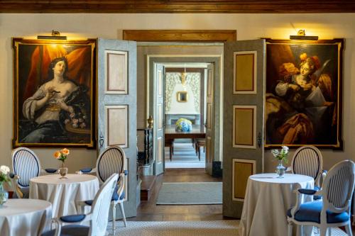 SantarValverde Santar Hotel & SPA - Relais & Châteaux的用餐室的墙壁上摆放着桌子和绘画作品