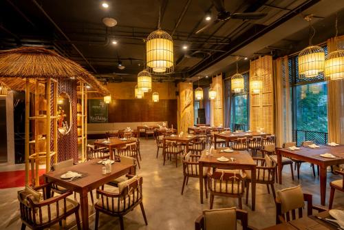 河内My Way Hotel & Residence Ha Noi的餐厅设有木桌和椅子及灯