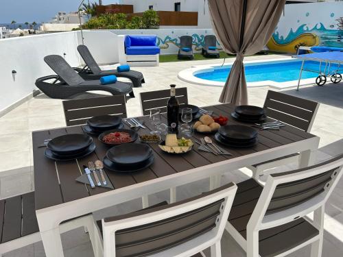 卡门港Casa Vedas - 3 bedroom villa with private pool的游泳池旁的餐桌上摆放着食物和葡萄酒