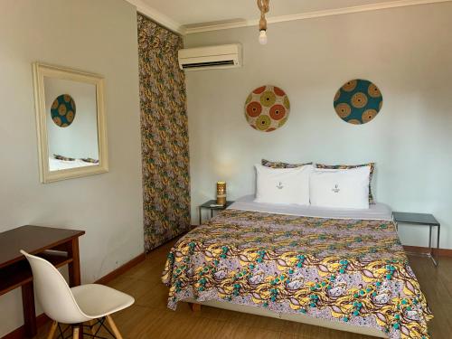 圣多美São Pedro Guesthouse的一间卧室配有一张床、一张桌子和一把椅子