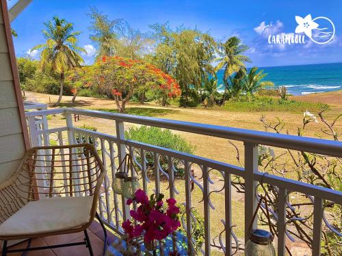 圣安尼STUDIO CARAMBOLE VUE MER - Piscines - Plages - Village vacances Sainte Anne Guadeloupe的一个带椅子的阳台,享有海滩美景