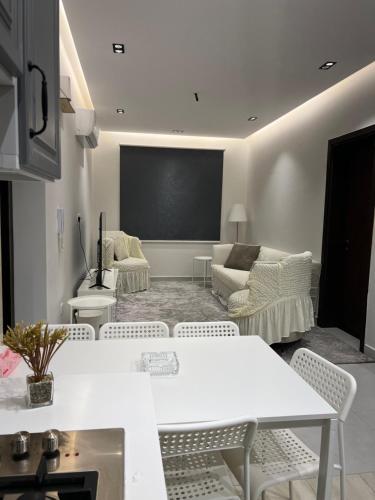 吉达اطلالة الريان شقة خاصة的客厅配有白色的桌椅和屏幕