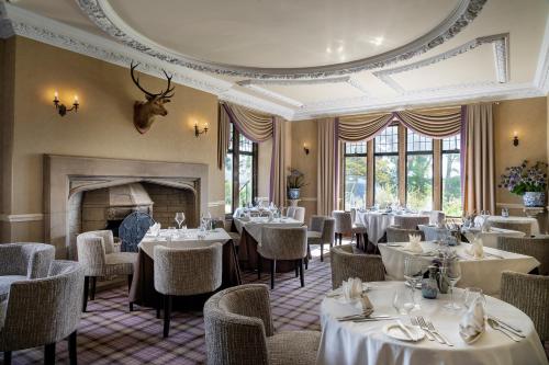 因弗戈登金格莱格城堡酒店的一间带桌椅和壁炉的用餐室