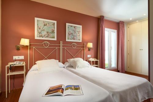 塞维利亚穆里略酒店的一间卧室配有一张大床,上面有书