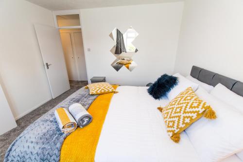 KentDartford Luxurious House with Parking - Netflix - Wi-Fi的一间卧室配有白色的床和黄色及蓝色枕头