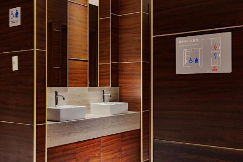 大阪Folio Sakura Shinsaibashi Osaka by Banyan Group的一间带两个水槽和木墙的浴室